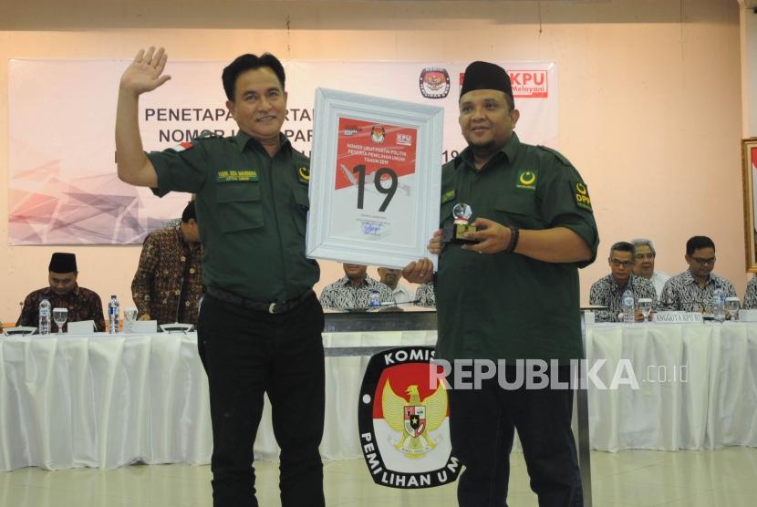 Ketua  Umum Partai Bulan Bintang Yusril Ihza Mahendra bersama Sekjen PBB Ferry Afriansyah Noor menunjukan nomor urut sembilan belas saat acara Pengundian Nomor Urut Peserta Pemilu 2019 di Kantor KPU, Jakarta, Ahad (18/2).