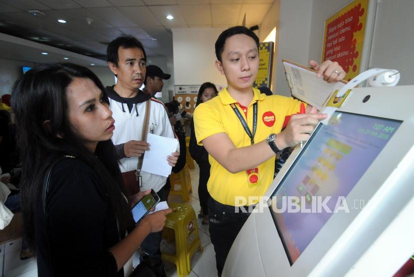 Petugas mengambilkan nomor antrian untuk warga yang akan melakukan registrasi ulang kartu SIM prabayar di Galeri Indosat, Kota Bogor, Jawa Barat, Rabu (28/2).