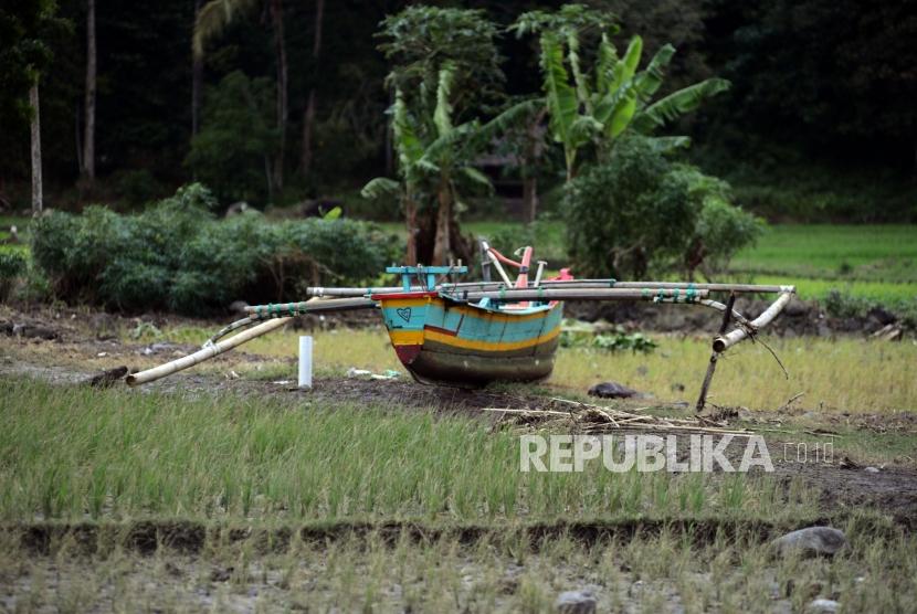 Perahu nelayan yang terdampar di area persawahan di Desa Way Uli, Kalianda, Lampung Selatan, Selasa (25/12).