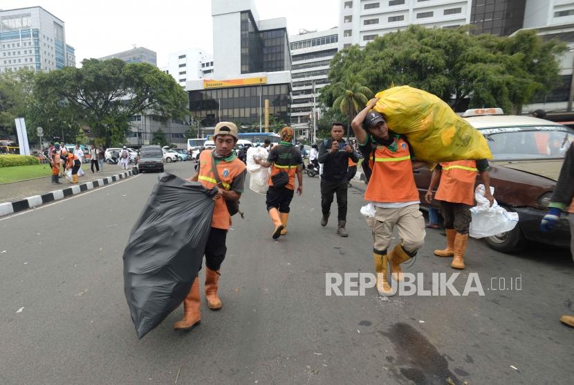 Petugas PPSU membersihkan sampah pasca aksi reuni 212 di kawasan Tugu Tani, Jakarta, Ahad (2/12).