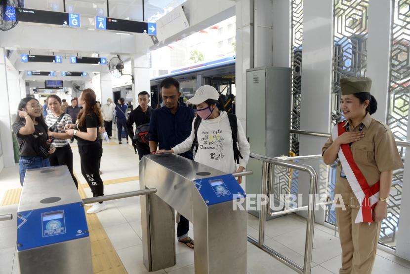 Petugas Transjakarta menyambut penumpang menggunakan kostum veteran di Halte Bundaran HI, Jakarta, Jumat (16/8).