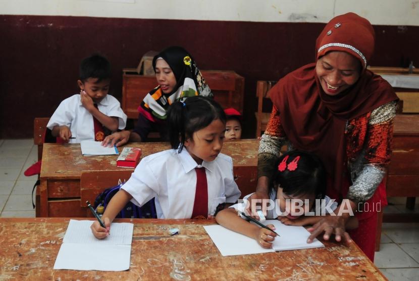 Warga menemani anaknya di dalam ruangan kelas pada hari pertama sekolah di SDN Mutiara, Desa Cibeber II, Leuwiliang, Kabupaten Bogor, Jawa Barat, Senin (16/7).