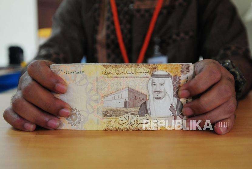 Petugas memperlihatkan mata uang Saudi Riyal di Asrama Haji Pondok Gede, Jakarta, Senin (23/7).