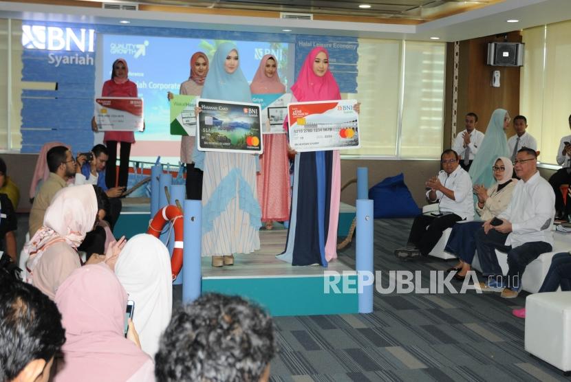 Direktur Utama BNI Syariah Abdullah Firman Wibowo (kanan duduk) menyaksikan para model yang sedang berpose membawa replika raksasa sejumlah produk dari BNI Syariah di sela acara pemaparan kinerja BNI Syariah Tahun 2018 di Kantor Pusat BNI Syariah Jakarta, Kamis  (14/2).