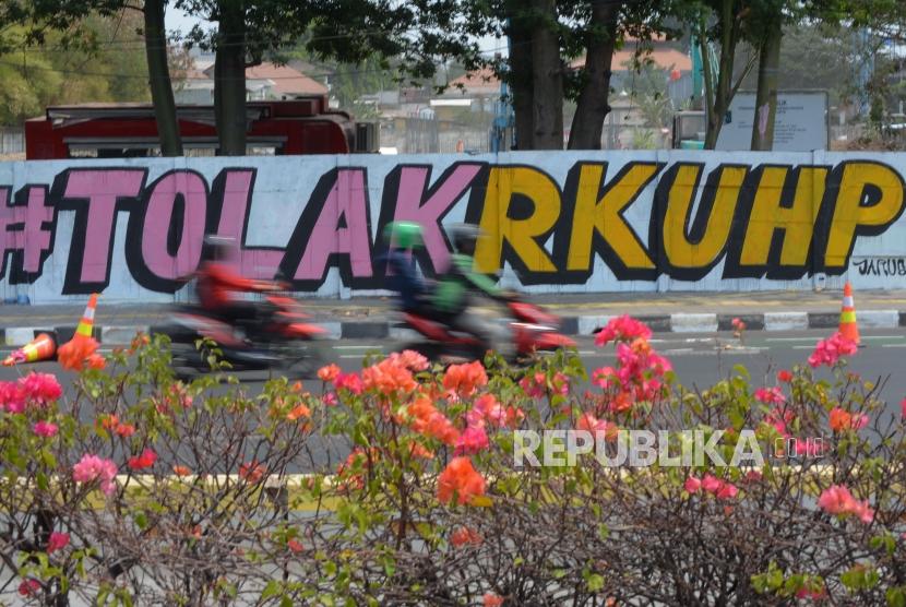 Pengendara melintas di area mural Tolak RUU RKUHP di Rawamangun, Jakarta Timur. Salah satu pasal kontroversial dalam RKUHP adalah mengenai penghinaan terhadap pemerintah.