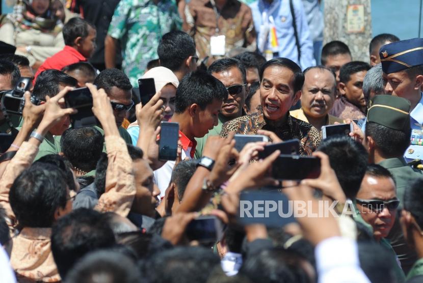 Presiden Republika Indonesia Ir Joko Widodo berjalan menyapa warga usai memberikan sambutan dalam acara puncak peringatan hari pers nasional 2018 di Danau Cimpago, Kota Padang, Provinsi Sumatra Barat, Jumat, (9/2).