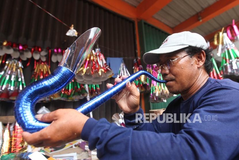 Pedagang mengecek suara terompet kertas yang sudah jadi di Kawasan Glodok, Jakarta, Rabu (27/12).