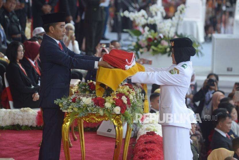 Presiden Republika Indonesia, Joko Widodo (kiri) menerima  duplikat bendera sang merah putih dari  Paskibraka Zanita Tahta  dalam upacara penurunan bendera sang merah putih di hari kemerdekaan Republik Indonesia ke 73 di  Istana Merdeka, Jakarta, Jumat (17/8).