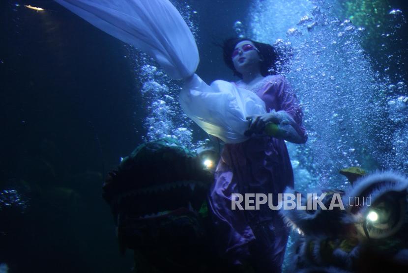 Seorang wanita berenang saat atraksi barongsai dan liong dalam air yang bertajuk The Battle of Yin Yang di Aquarium Utama Seaworld Ancol, Jakarta, Jumat (16/2).