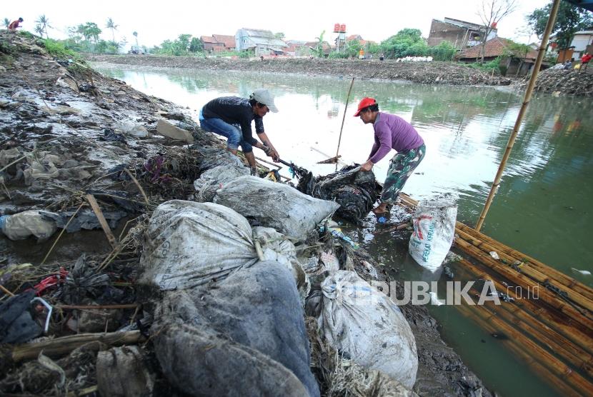 Dua penduduk berusaha mengangkat sampah Sungai Citraum, di Sektor enam program Citarum Harum Kodam III/Siliwangi, Kecamatan Bojongsoang, Kabupaten Bandung, Selasa (24/4).