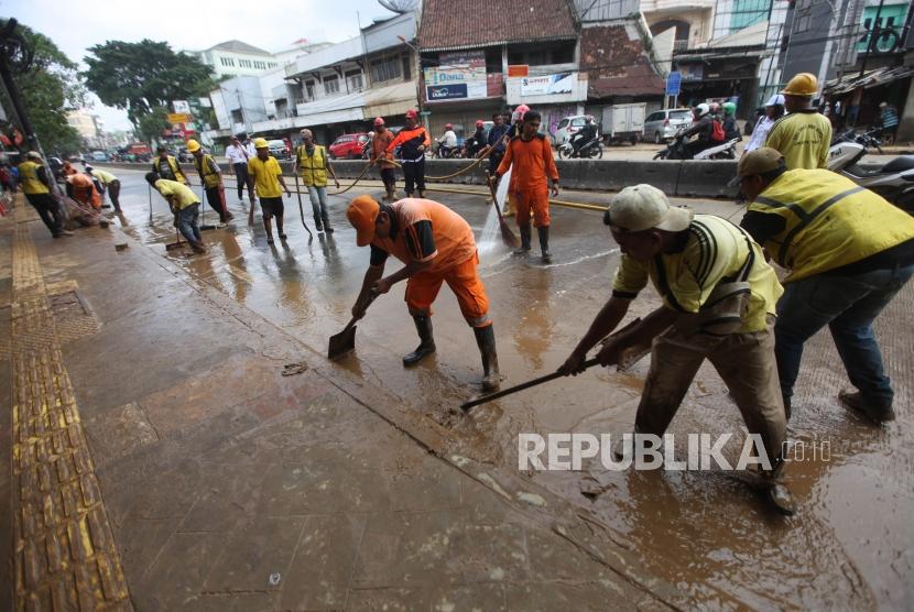 Petugas PPSU dan Bina Marga membersihkan lumpur pascabanjir di Ruas Jalan Jatinegara Barat, Jakarta, Rabu (7/2).