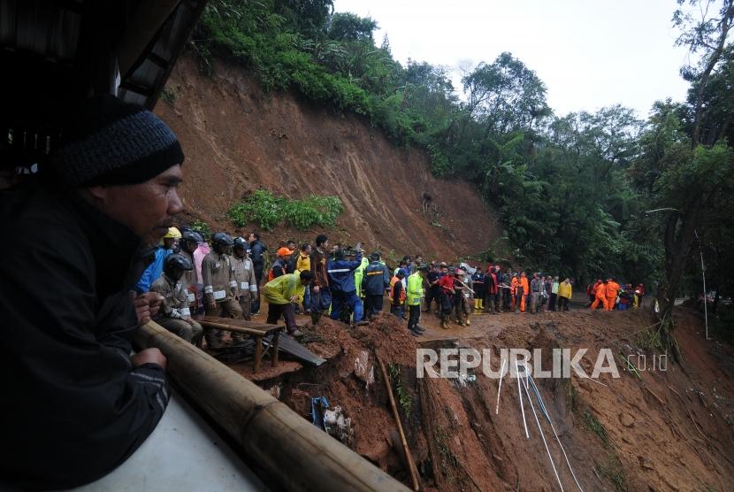 Warga melihat petugas gabungan melakukan evakuasi longsor di Jalur Utama Puncak, Bogor, Jawa Barat, Senin (5/2).
