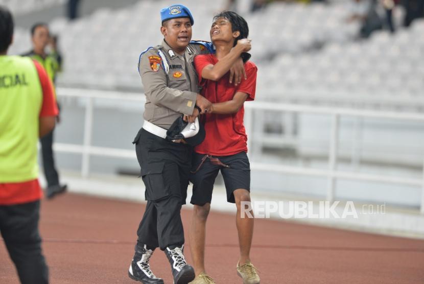 Petugas keamanan mengamankan seorang suporter timnas Indonesia yang berusaha masuk kedalam lapangan saat pertandingan Kualifikasi babak kedua Piala Dunia 2022 zona Asia melawan Malaysia di Stadion Gelora Bung Karno, Senayan, Jakarta, Kamis (5/9).