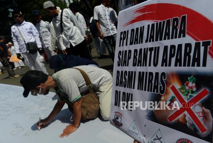 Aksi Dukung Pelepasan Saham Bir. Sejumlah massa PA 212 dan Jawara Betawi membubuhkan tanda tangan saat melakukan aksi di Jalan kebon Sirih, Jakarta, Jumat (8/3).