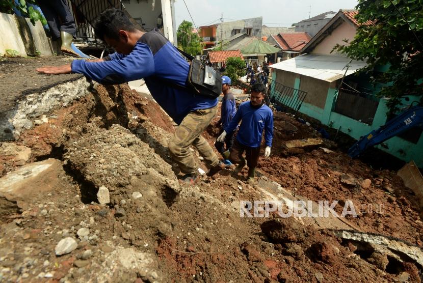 Sejumlah petugas melintasi longsoran tanah yang menghancurkan satu rumah di Perumahan Pesona Kalisari, Pasar Rebo, Jakarta Timur, Selasa (27/11).