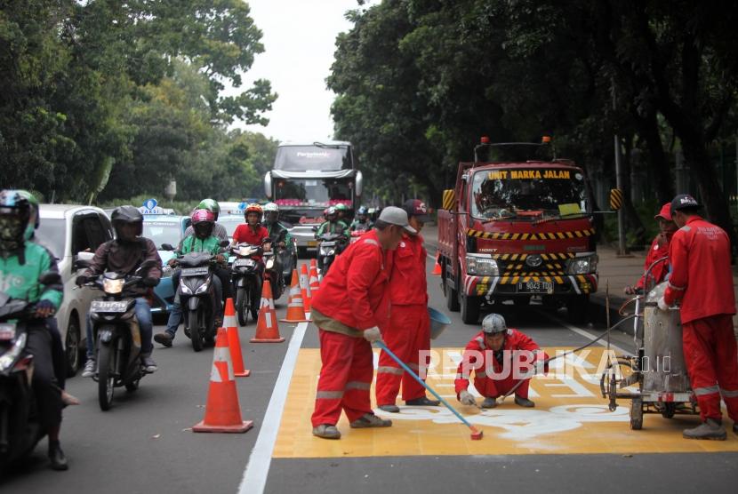 Pekerja mengecat jalur kuning khusus sepeda motor di Kawasan Jalan Merdeka Barat, Jakarta, Rabu (17/1).
