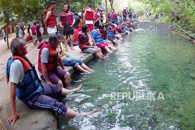 Pengunjung menikmati terapi ikan di objek wisata alam Sungai Citumang, Kabupaten Pangandaran, Jumat (27/9).