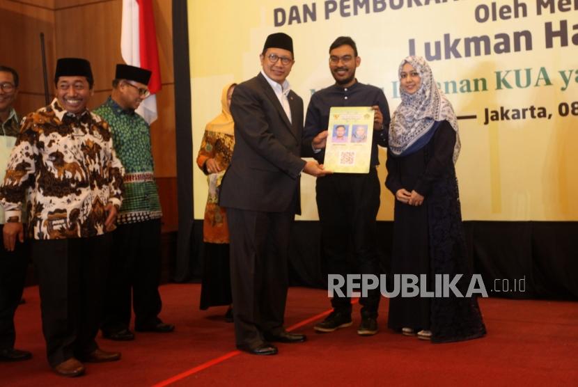 Menteri Agama Lukman Hakim Saifuddin menyerahkan kartu nikah kepada pasangan suami istri seusai peresmian Aplikasi Pencatatan Nikah (SIMKAH) Web dan Kartu Nikah di Auditorium Kementerian Agama, Jakarta, Kamis (8/11).