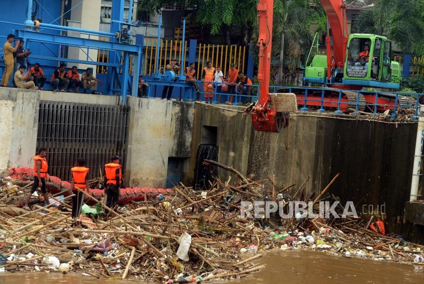Petugas Dinas Kebersihan DKI Jakarta saat membersihkan sampah yang menumpuk di Pintu Air Manggarai, Jakarta, Senin (12/11).