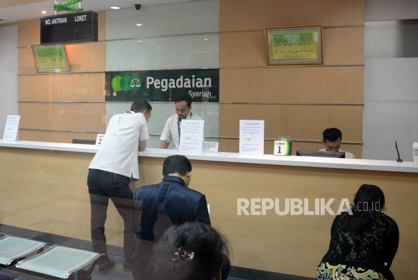 Petugas melayani nasabah ketika bertransaksi di kantor pelayanan Pegadaian Syariah, Jakarta, Jumat (4/1). Tiga tahun terakhir, omzet Pegadaian syariah mengalami tren peningkatan.