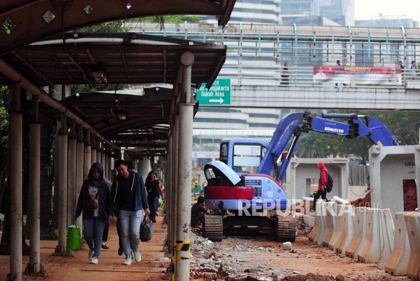 Warga berjalan kaki di dekat proyek penataan trotoar di kawasan Sudirman, Jakarta Pusat, Jumat (29/6).