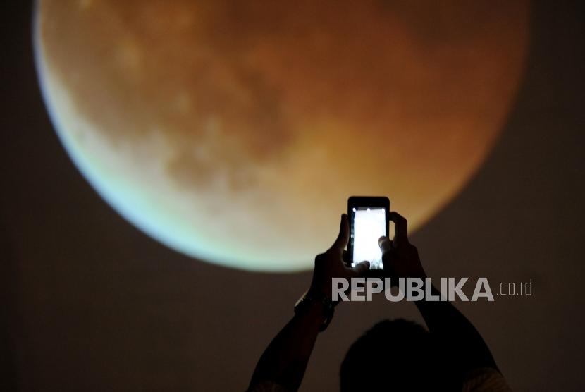 A Jakarta resident takes a photograph of total lunar eclipse at Taman Ismail Marzuki (TIM), Cikini, Jakarta, on Wednesday (Jan 31).