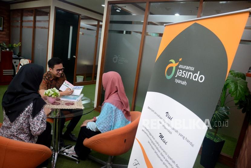 Karyawan memberikan informasi produk kepada calon pesesrta di kantor Asuransi Jasindo Syariah, Jakarta.