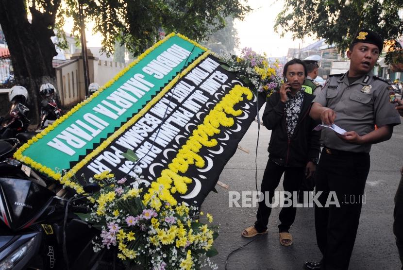 Polisi memeriksa karangan bunga duka cita pasca insiden kerusuhan antara petugas kepolisian dan narapidana di Mako Brimob, Depok, Jawa Barat, Kamis (10/5).