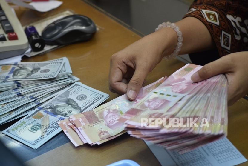 Petugas menghitung mata uang rupiah dan dolar AS di salah satu tempat penukaran uang di Jakarta, Jumat (9/11).