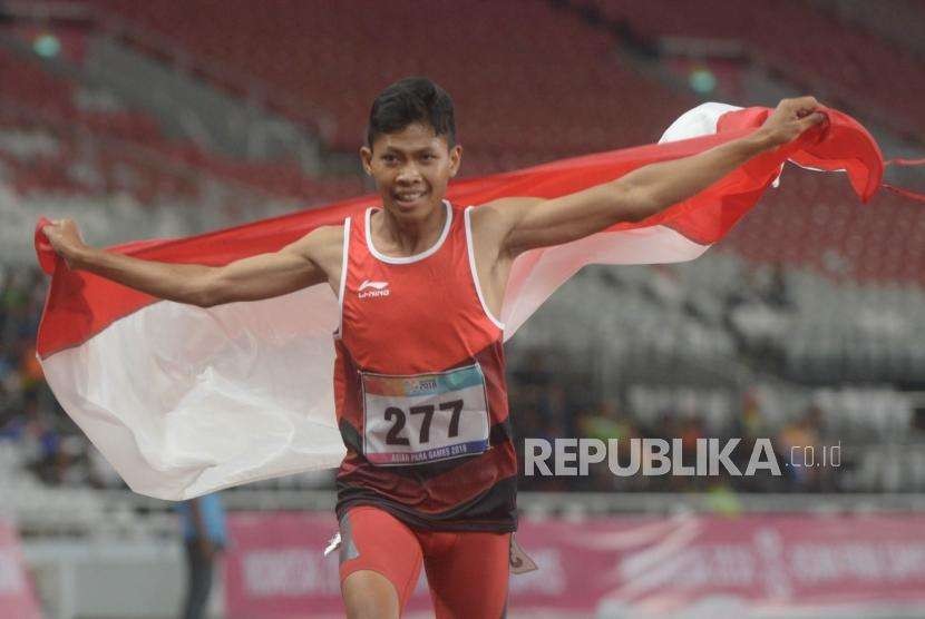 Sprinter Indonesia Sapto Yogo Purnomo berlari sambil membawa bendera Merah-Putih usai menjuarai final 100 meter putra T37 Asian Para Games di Stadion Utama Gelora Bung Karno, Senayan, Jakarta, Selasa  (9/10).
