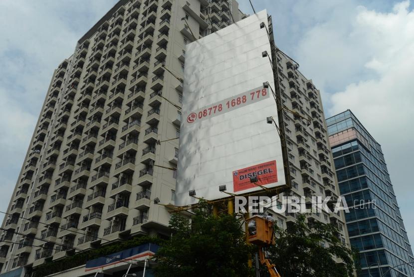 Petugas usai menyegel papan reklame di Jalan Gatot Subroto, Jakarta, Senin (14/1).