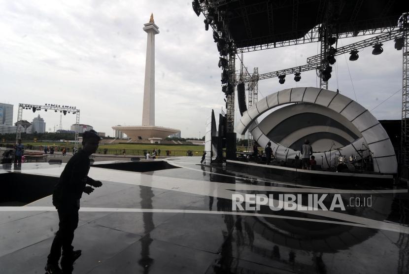 Pekerja melintasi panggung yang didirikan di kawasan Monas, Jakarta Pusat, Jumat (29/12).