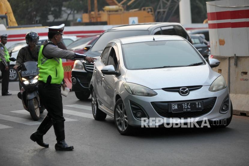 Polisi memberhentikan kepada pengendara bernomor polisi genap saat sistem ganjil genap di Kawasan Pancoran, Jakarta, Rabu (1/8).
