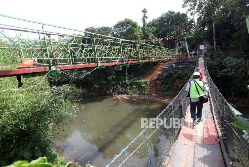 Pekerja melintas disamping pembangunan jembatan gantung di kawasan Srengseng Sawah, Jagakarsa, Jakarta, Jumat (3/8).