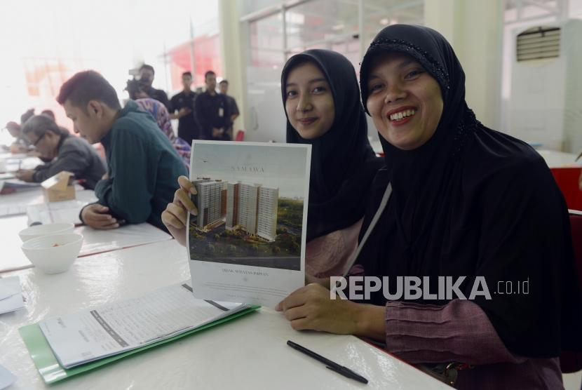 Warga memperlihatkan gambar Rusunami Klapa Village saat melakukan verifikasi pendaftar kredit dan pemilihan unit Program Samawa Rumah DP 0 Rupiah di Jakarta, Ahad (28/7).