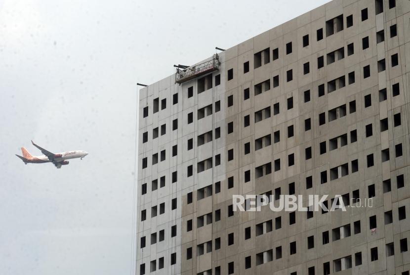 Pesawat melintas di dekat proyek pembangunan Rumah Susun Milik (Rusunami) Klapa Village di kawasan Pondok Kelapa, Jakarta, Kamis (11/4).(Republika/Putra M. Akbar)