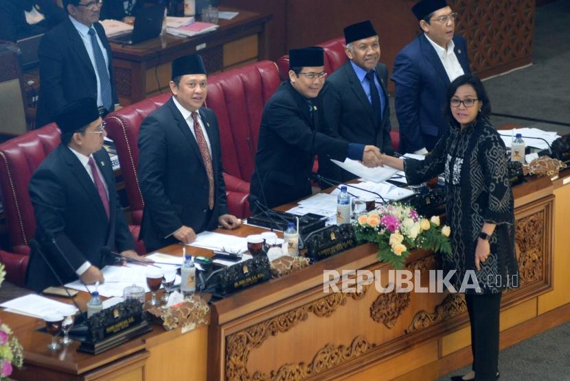 Menteri Keuangan Sri Mulyani (depan) berjabat tangan dengan Wakil Ketua DPR Taufik Kurniawan (tengah) disaksikan Pimpinan DPR lainnya saat pengambilan keputusan RUU dalam rapat paripurna DPR di Kompleks Parlemen, Senayan, Jakarta, Kamis (26/4).