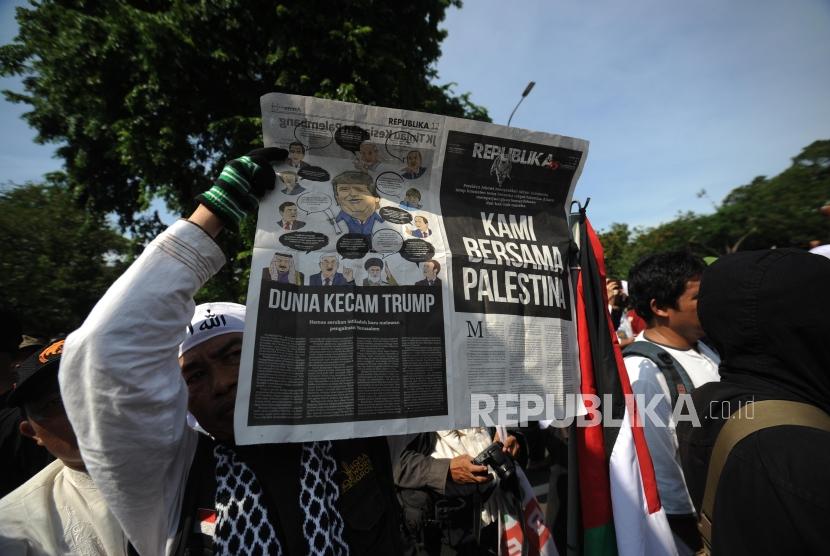 Peserta Aksi. Peserta aksi membentangkan koran Harian Republika  dalam  aksi damai di depan kantor Kedutaan Amerika Sertikat, Jakarta, Jumat (08/12).