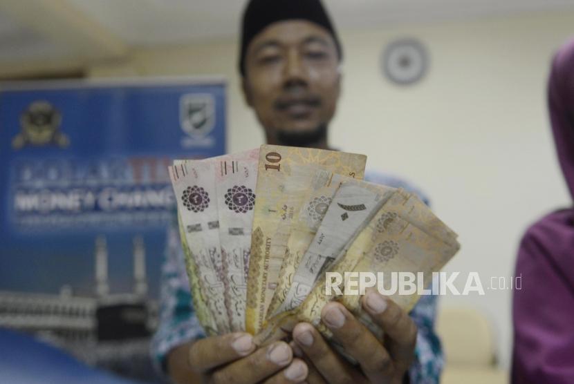 Calon jamaah haji memperlihatkan mata uang Saudi Riyal di Asrama Haji Pondok Gede, Jakarta, Rabu (17/7).