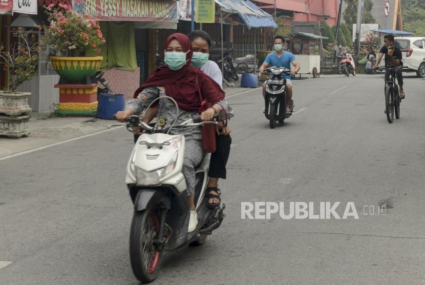 Warga mengendarai motor saat asap kebakaran lahan gambut menyelimuti Alun-alun Kabupaten Siak, Riau, Kamis (12/9).