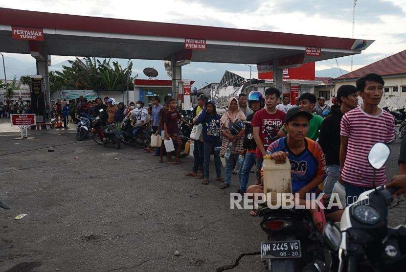 Warga mengantre untuk mengambil BBM yang didapat dari tangki penyimpanan bahan bakar di SPBU, Palu, Sulawesi Tengah, Ahad (30/9).