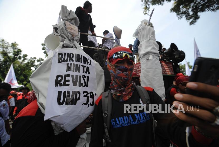 Seorang buruh berswa foto dalam aksi demo di depan Balaikota DKI Jakarta, Jumat(10/11). Aksi unjuk rasa ini bertujuan menolak upah murah dan meminta Gubernur DKI Jakarta Anies Baswedan untuk merevisi UMP DKI Jakarta.