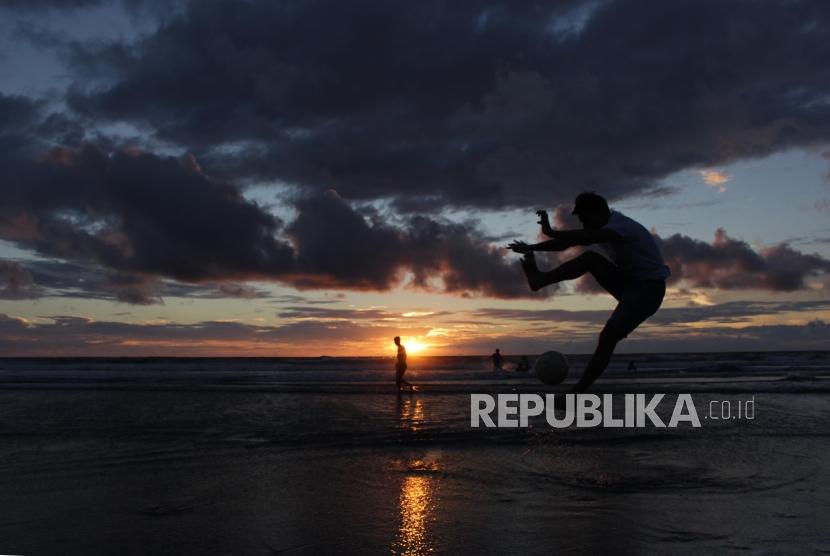 Wisatawan bermain bola di pantai Kuta, Bali, Selasa (6/2).