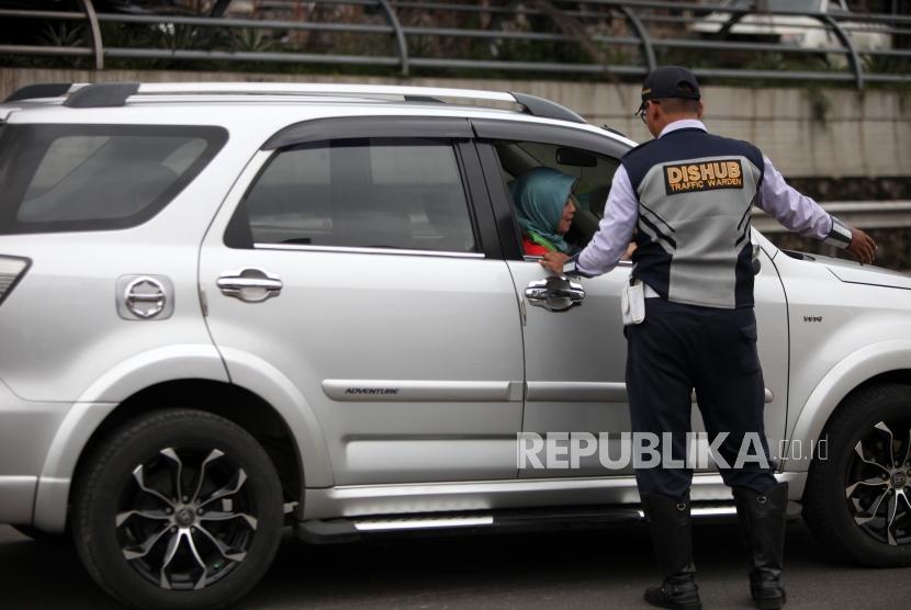 Petugas Dishub mengarahkan kepada pengendaran mobil bernomor polisi ganjil saat hari pertama pemberlakuan sistem ganjil genap di Gerbang Tol Bekasi Barat 1, Bekasi, Jawa Barat, Senin (12/3).