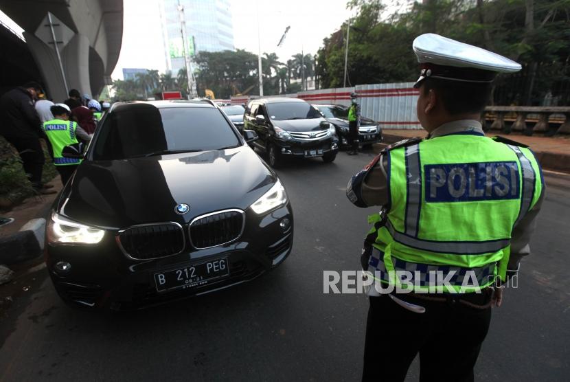 Polisi memberhentikan kepada pengendara bernomor polisi genap saat sistem ganjil genap di Kawasan Pancoran, Jakarta, Rabu (1/8).