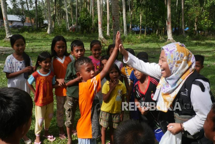 Seorang relawan ACT bermain dengan anak-anak di desa Lompio Kabupaten Sirenja, Donggala Sulawesi Tengah, Ahad (14/10).
