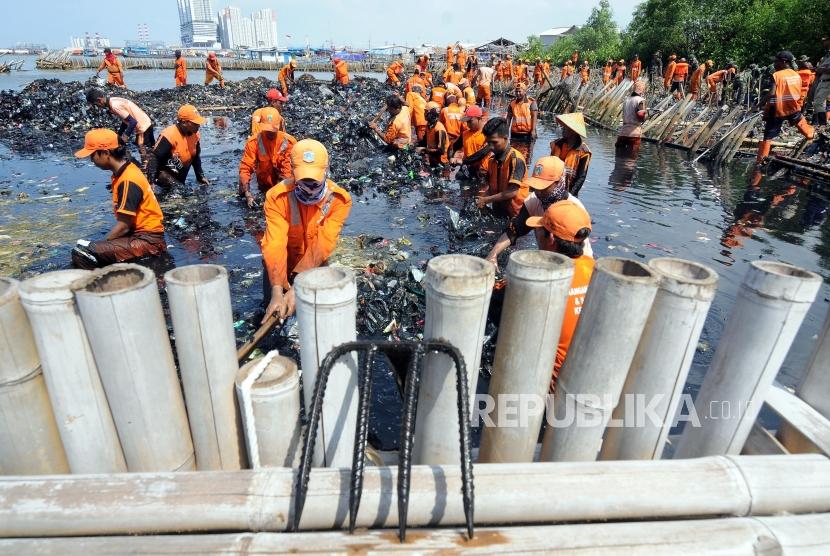 Sejumlah petugas saat membersihkan sampah yang menumpuk di Muara Angke, Jakarta Utara Senin (19/3).
