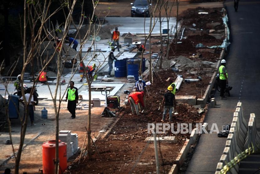 Sejumlah pekerja menyelesaikan proyek pembangunan pedestrian di Jalan Sudirman, Jakarta, Ahad (1/7).