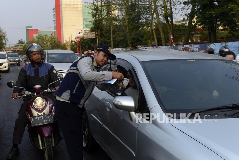 Petugas Dinas Perhubungan DKI Jakarta saat melakukan sosialisasi uji coba perluasan sistem ganjil genap kepada pengendara di kawasan Pramuka, Jakarta, Senin (12/8).