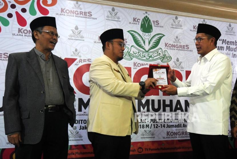 Ketua PP Muhammadiyah Yunahar Ilyas bersama Ketua Umum PP Pemuda Muhammadiyah Dahnil Anzar Simanjuntak dan Menteri Agama Lukman Hakim Saifuddin (dari kiri) usai memberikan cinderamata pada pembukaan Kongres Ulama Muda Muhammadiyah di Aula Gedung Dakwah Muhammadiyah, Menteng, Jakarta, Selasa (30/1).